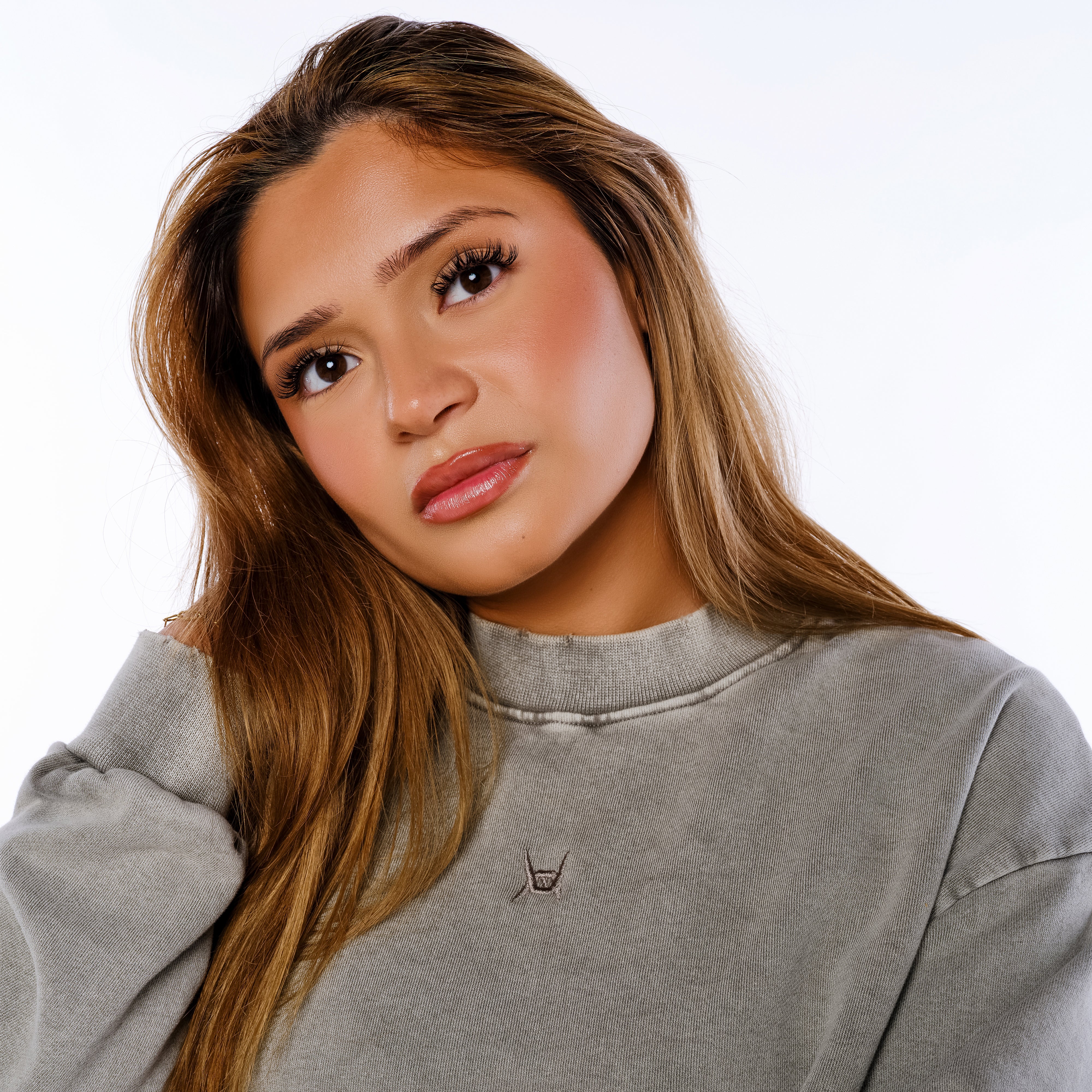 Woman wearing a gray sweatshirt with a brand logo on a white background