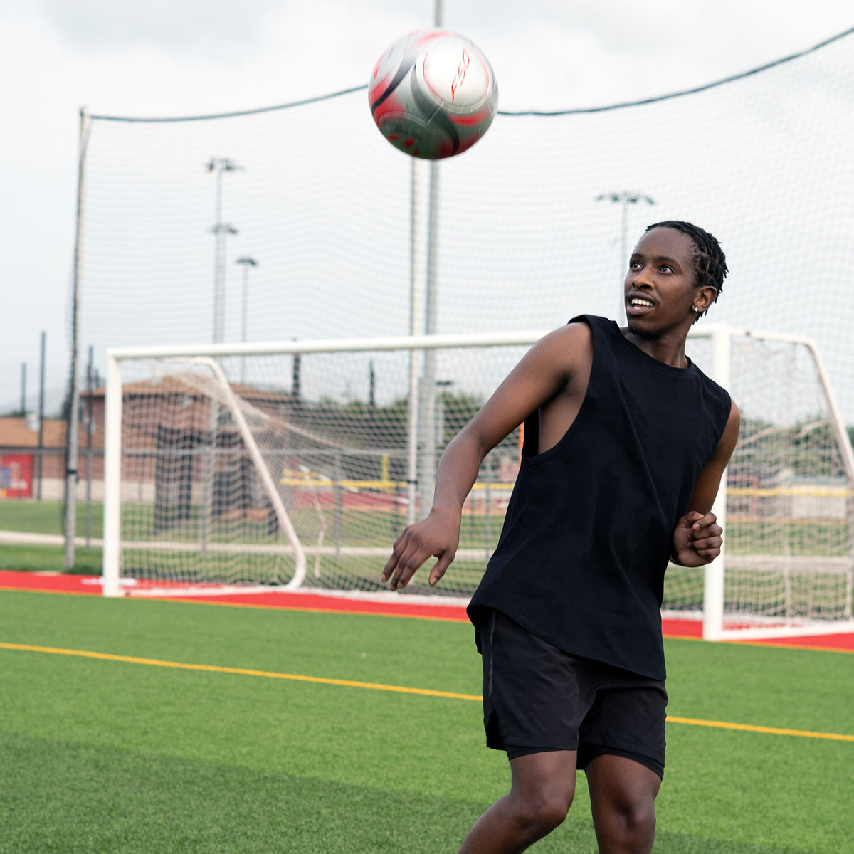 Athlete wearing black loose-fit muscle tank while heading a soccer ball